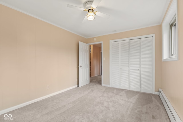 unfurnished bedroom featuring light colored carpet, baseboard heating, crown molding, ceiling fan, and a closet