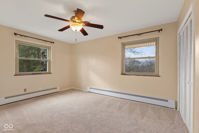 unfurnished bedroom featuring ceiling fan, a closet, multiple windows, and a baseboard heating unit