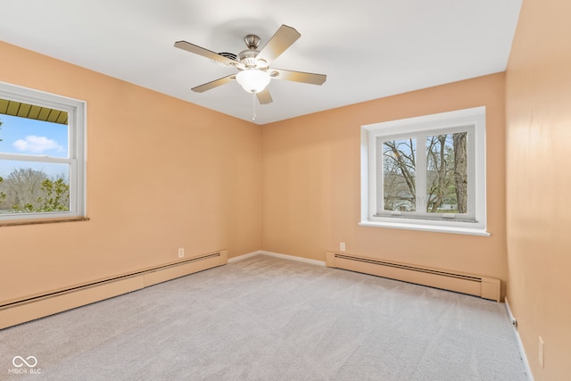 spare room with light colored carpet, a wealth of natural light, and a baseboard heating unit