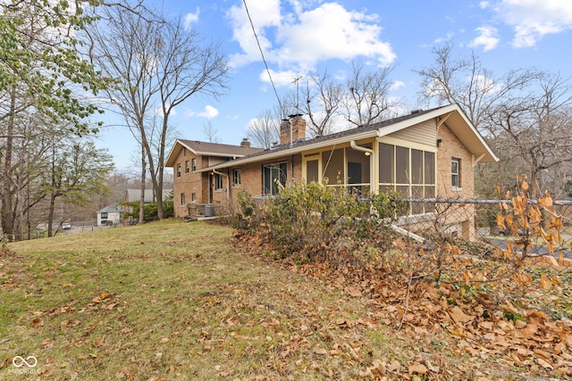 back of house featuring a sunroom, a lawn, and central AC