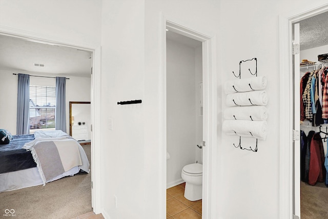 bathroom with toilet, a textured ceiling, and tile patterned floors