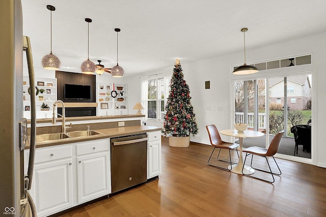 kitchen with stainless steel dishwasher, dark wood-type flooring, sink, pendant lighting, and white cabinetry