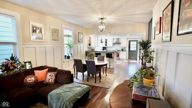 living room with a decorative wall, wainscoting, a textured ceiling, and wood finished floors