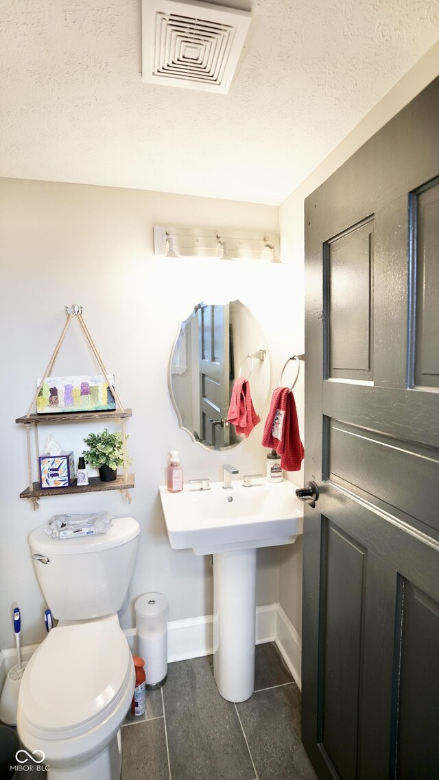 bathroom featuring baseboards, visible vents, tile patterned flooring, a textured ceiling, and toilet