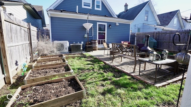 back of property with a patio, a garden, a fenced backyard, central AC, and ac unit