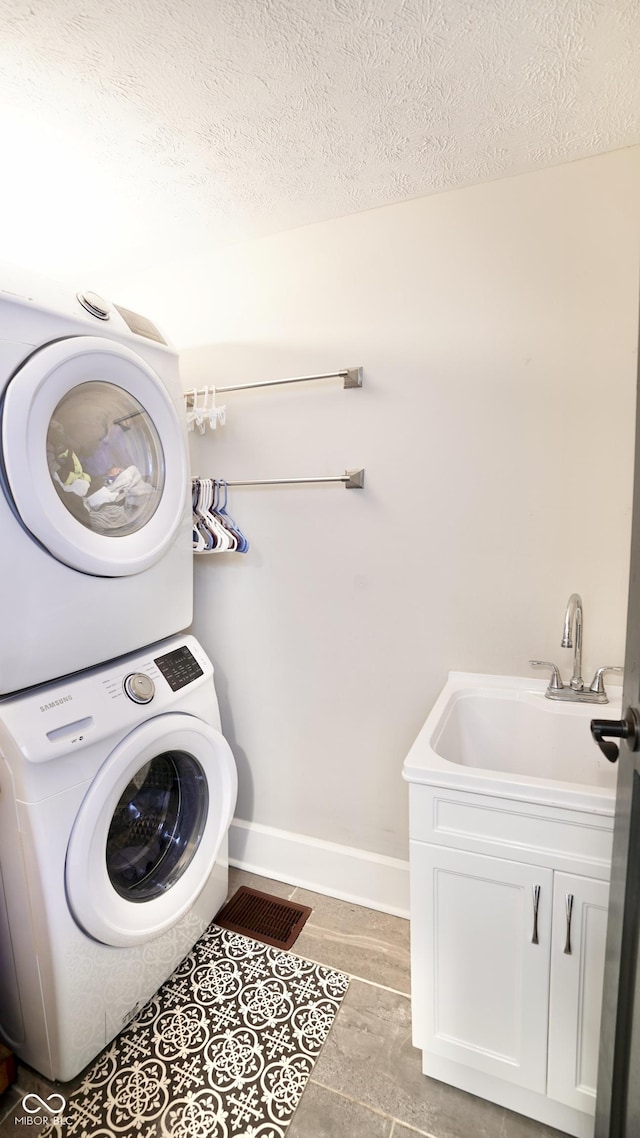 washroom featuring a sink, a textured ceiling, laundry area, and stacked washing maching and dryer