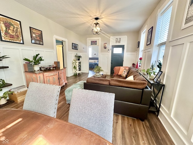 living area with a chandelier, a wainscoted wall, dark wood finished floors, and a decorative wall