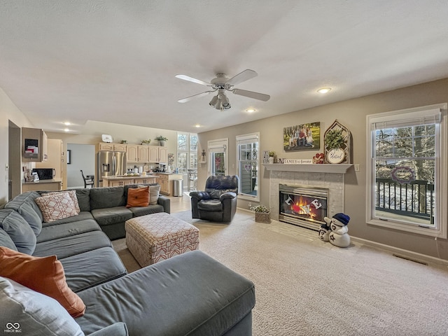 carpeted living room with a tiled fireplace and ceiling fan