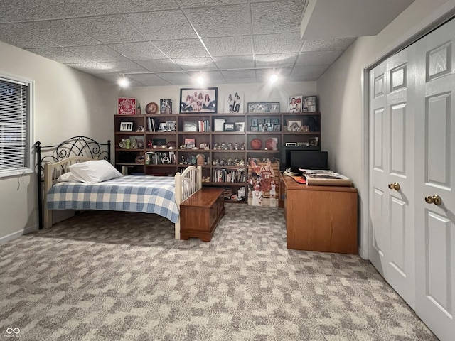 bedroom with a closet, a paneled ceiling, and carpet floors