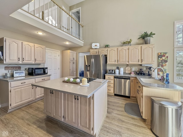 kitchen with a kitchen island, sink, a towering ceiling, and black appliances