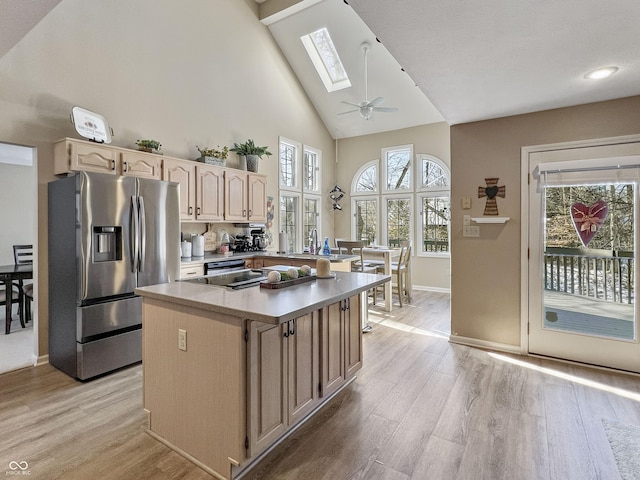 kitchen featuring appliances with stainless steel finishes, a kitchen island, a skylight, and light hardwood / wood-style floors