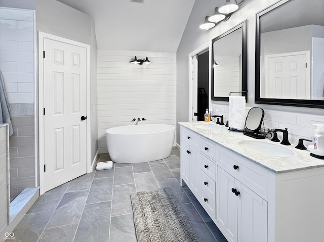 bathroom with vanity, a bathing tub, and lofted ceiling