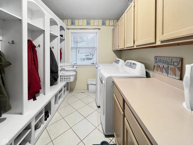 clothes washing area featuring washing machine and clothes dryer, light tile patterned floors, cabinets, and a textured ceiling