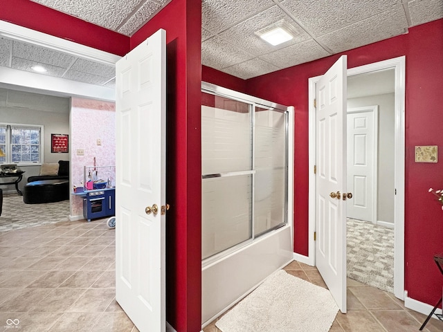 bathroom featuring a drop ceiling, bath / shower combo with glass door, and tile patterned flooring