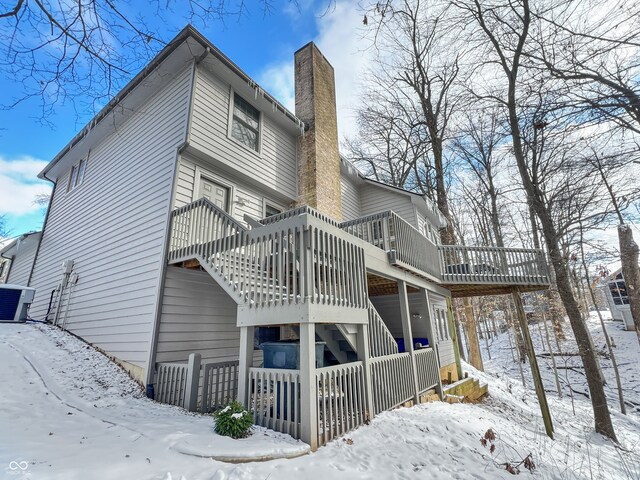 snow covered house featuring central AC and a deck