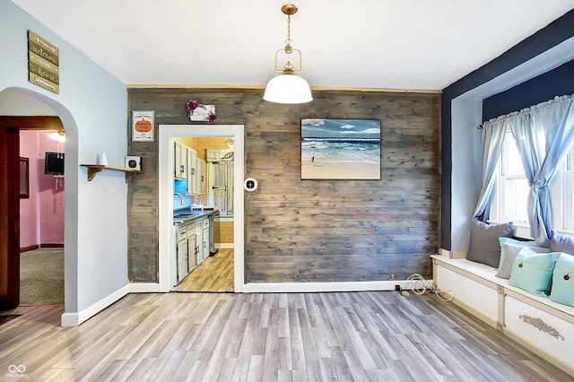 unfurnished dining area with wood walls, light hardwood / wood-style floors, and sink