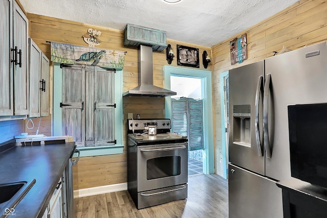 kitchen featuring wood walls, light wood-type flooring, extractor fan, and appliances with stainless steel finishes