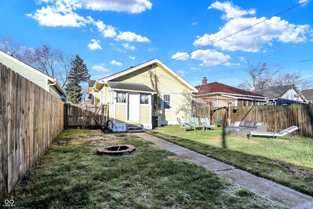 rear view of property with a yard, an outdoor living space with a fire pit, and an outdoor structure