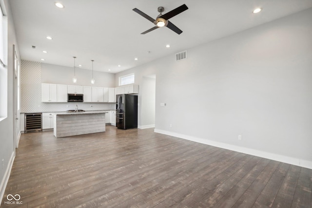 kitchen featuring wine cooler, dark hardwood / wood-style floors, a kitchen island with sink, and appliances with stainless steel finishes