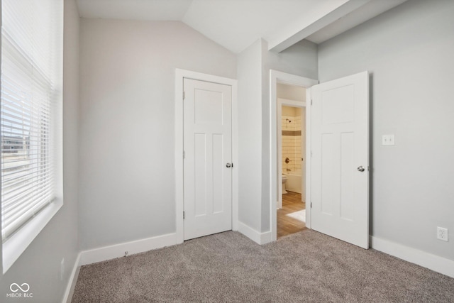 unfurnished bedroom featuring light carpet and vaulted ceiling