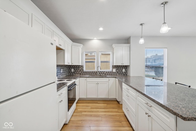 kitchen featuring white cabinetry, sink, light hardwood / wood-style flooring, decorative light fixtures, and white appliances