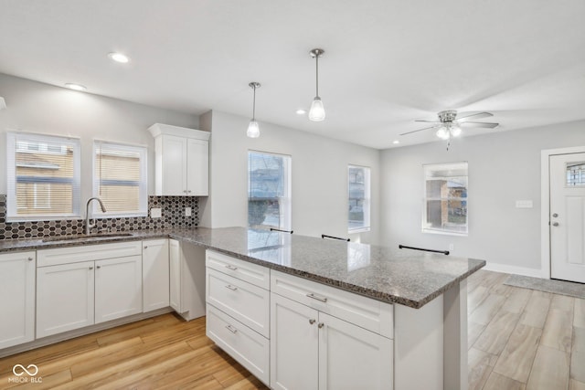 kitchen with white cabinets, light hardwood / wood-style flooring, a wealth of natural light, and sink