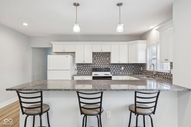 kitchen with white appliances, sink, light hardwood / wood-style flooring, white cabinets, and hanging light fixtures