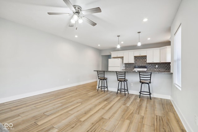 kitchen featuring white cabinetry, white refrigerator, pendant lighting, decorative backsplash, and light wood-type flooring