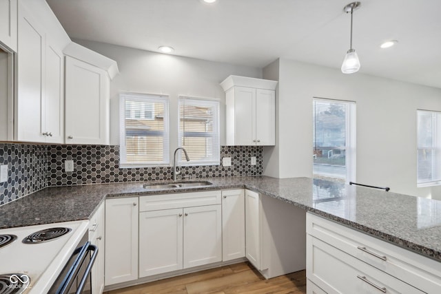 kitchen with tasteful backsplash, sink, dark stone countertops, white cabinets, and light hardwood / wood-style floors