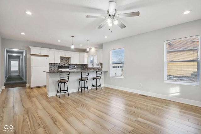 kitchen featuring white refrigerator, white cabinetry, kitchen peninsula, and light hardwood / wood-style flooring