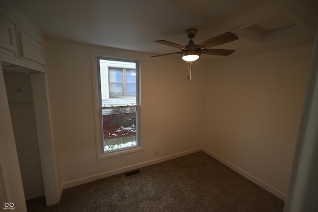 spare room featuring ceiling fan and dark carpet