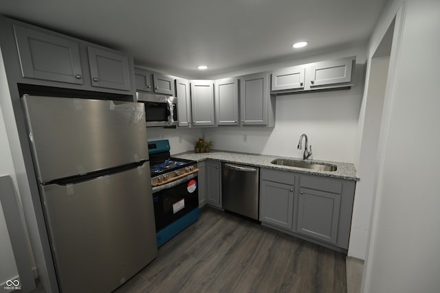 kitchen featuring light stone countertops, dark hardwood / wood-style flooring, gray cabinetry, stainless steel appliances, and sink