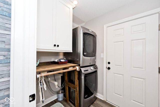 laundry room with cabinets, dark hardwood / wood-style flooring, and stacked washing maching and dryer