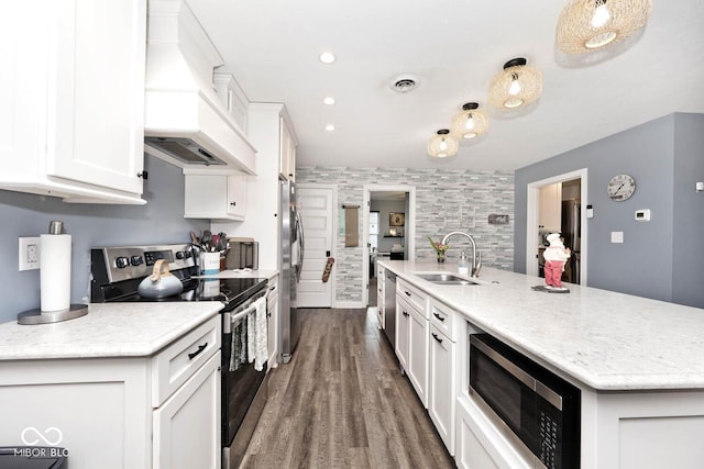 kitchen featuring appliances with stainless steel finishes, custom range hood, sink, a center island with sink, and white cabinets