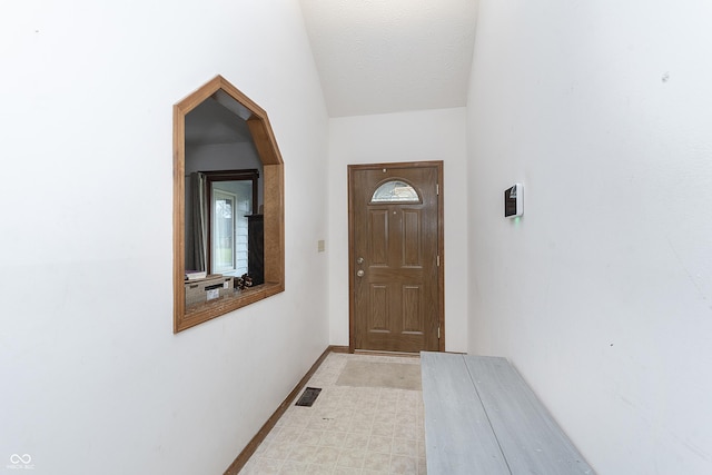 doorway featuring lofted ceiling and a textured ceiling