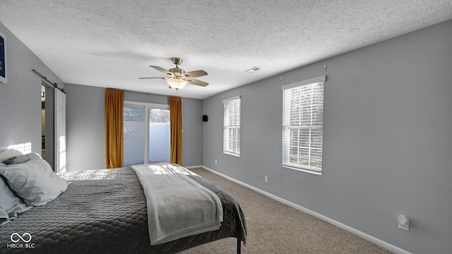 bedroom with carpet, a textured ceiling, a barn door, and ceiling fan