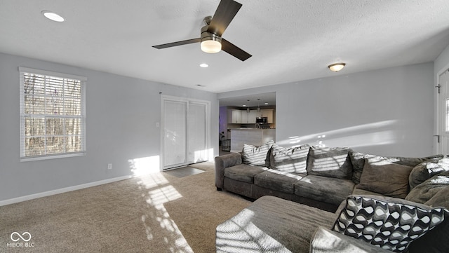 carpeted living room featuring a textured ceiling and ceiling fan