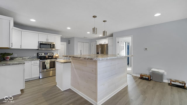 kitchen featuring white cabinets, decorative light fixtures, a kitchen island, and appliances with stainless steel finishes