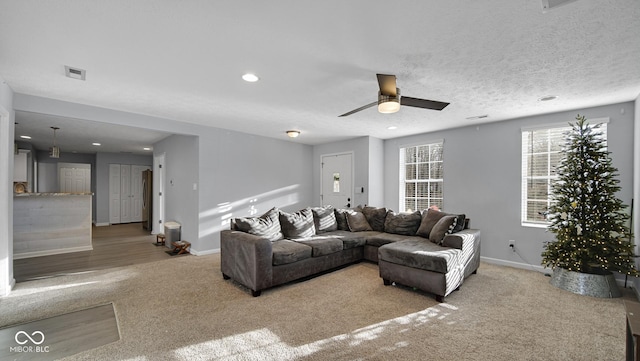 living room with a textured ceiling, light hardwood / wood-style floors, and ceiling fan