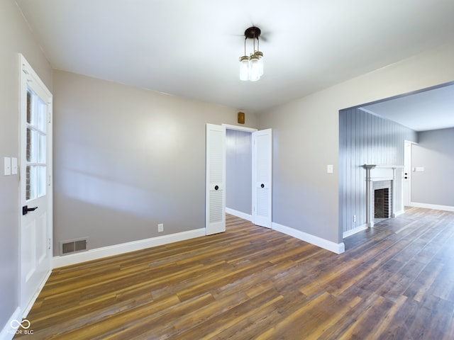 unfurnished room featuring dark hardwood / wood-style floors and a brick fireplace