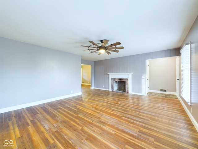 unfurnished living room with ceiling fan, wood-type flooring, and a fireplace