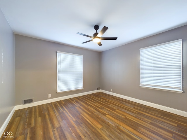 empty room featuring a wealth of natural light, ceiling fan, and dark hardwood / wood-style floors