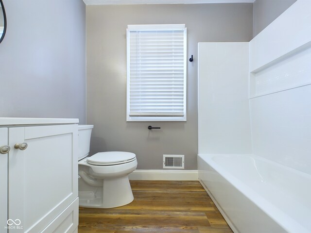 bathroom with hardwood / wood-style flooring, vanity, a bathtub, and toilet