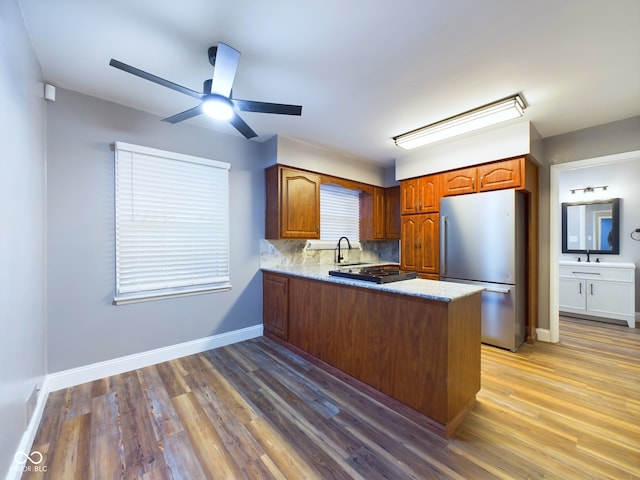 kitchen with stainless steel refrigerator, ceiling fan, kitchen peninsula, and wood-type flooring