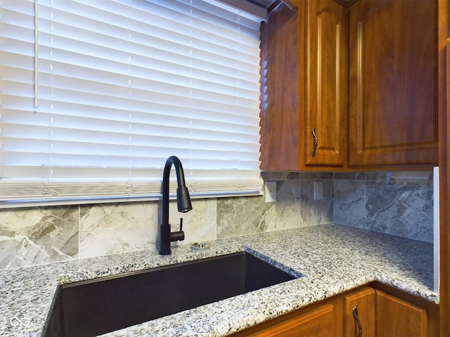 interior details with backsplash, light stone countertops, and sink