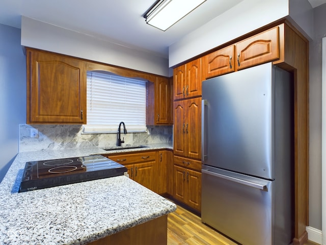 kitchen featuring decorative backsplash, stainless steel fridge, light hardwood / wood-style flooring, and sink