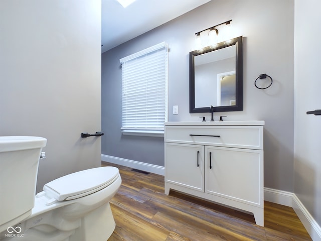 bathroom featuring toilet, vanity, a healthy amount of sunlight, and hardwood / wood-style flooring