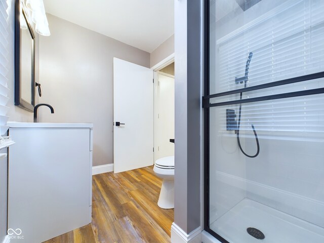 bathroom with walk in shower, toilet, and hardwood / wood-style flooring