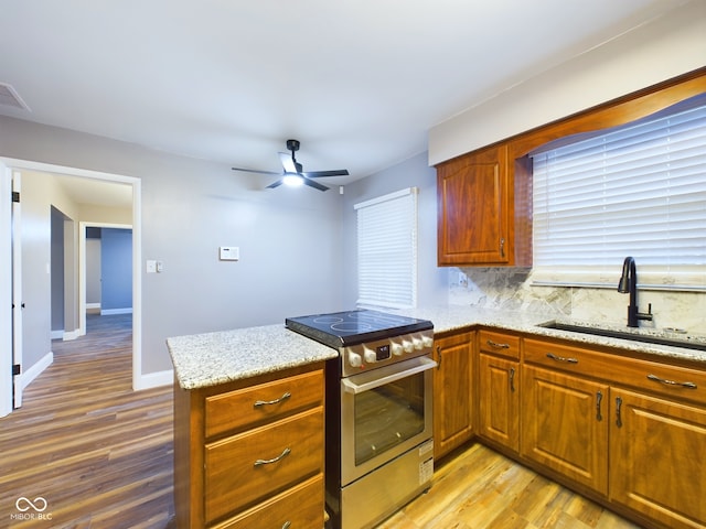 kitchen with kitchen peninsula, tasteful backsplash, light hardwood / wood-style floors, sink, and stainless steel stove