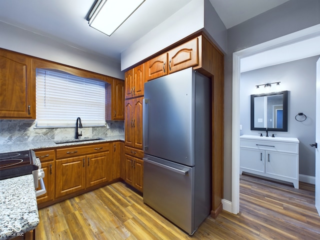 kitchen featuring light stone countertops, backsplash, sink, dark hardwood / wood-style floors, and stainless steel refrigerator